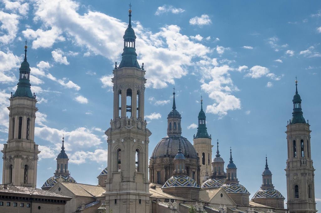 View of Basilica del Pilar with ornate towers and domes under blue sky in Zaragoza, Aragón