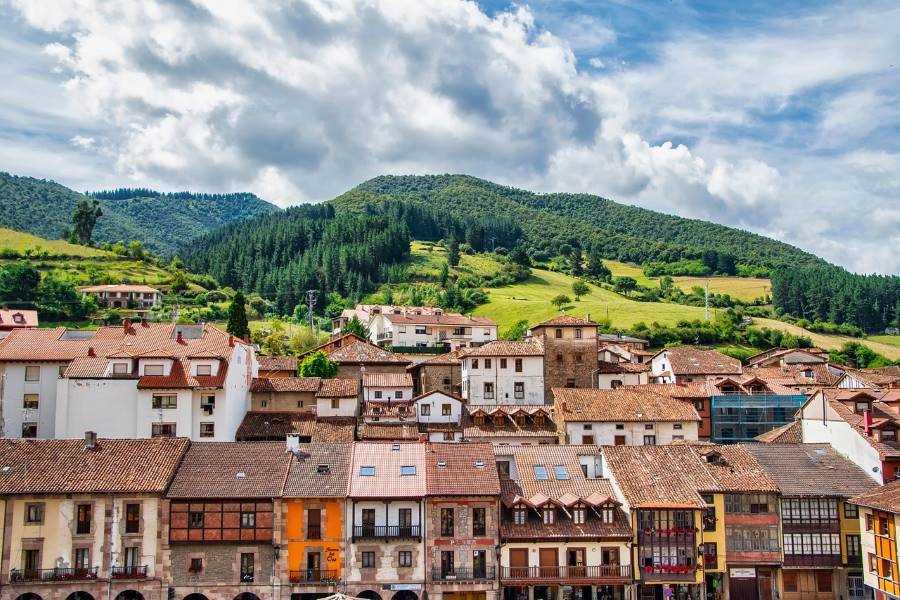 Scenic view of Potes in Cantabria with stone houses, red roofs and green forested hills