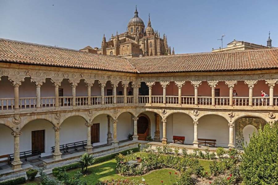 View of a Renaissance cloister in Salamanca with the dome of the cathedral rising in the background